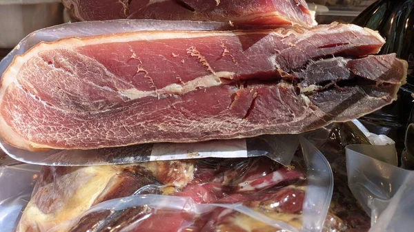 stock image A large piece of pork meat, cured in a bag, stands on a table at a fair in Portugal