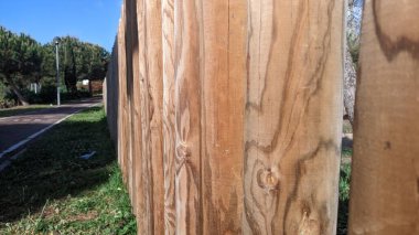 Koşu bandının yanında yere saplanmış yuvarlak kerestelerden yapılmış bir çit var.