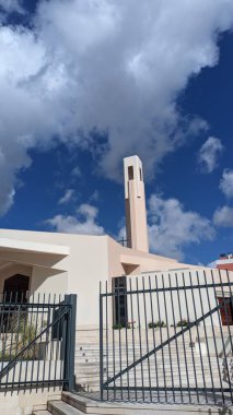 Beyaz duvarları ve mavi gökyüzüne karşı yüksek kulesi olan modern bir kilise.