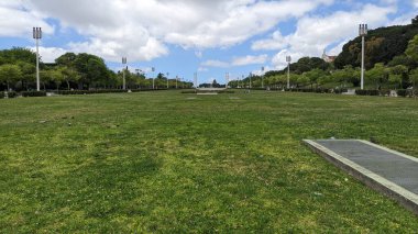 Lizbon 'un merkezindeki parkta büyük, uzun bir çimenlik, mavi gökyüzü ve bulutlu bir fotoğraf.