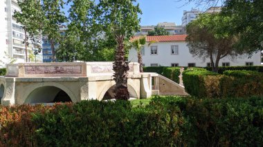 11.02.2023 Park Parkı 'ndaki eski çeşme, Lizbon' daki kırpılmış çalılıkların ve yüksek binaların zeminine karşı.