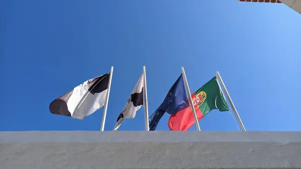 Four flags on top of four pillars of their metal against a blue sky Portugal European Union photo