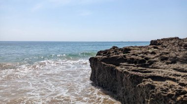 Lizbon 'da okyanus kıyısında koyu kahverengi kayalar, Carcavelos, Portekiz fotoğrafı.