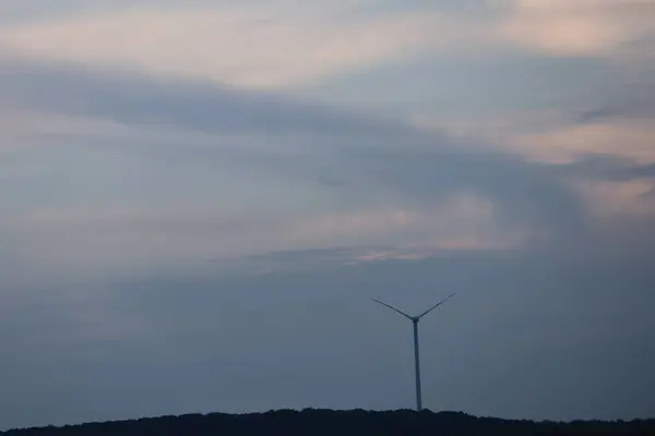 Ufukta rüzgar fotoğrafından elektrik üreten büyük bir rüzgar türbini var.