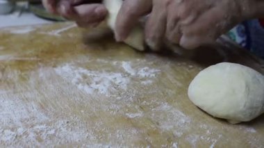 Bir insan ahşap bir kesme tahtasındaki hamurla çalışıyor, suyu malzeme olarak kullanıyor. Sahne toprak, ahşap ve vahşi yaşam elementleriyle karasal.