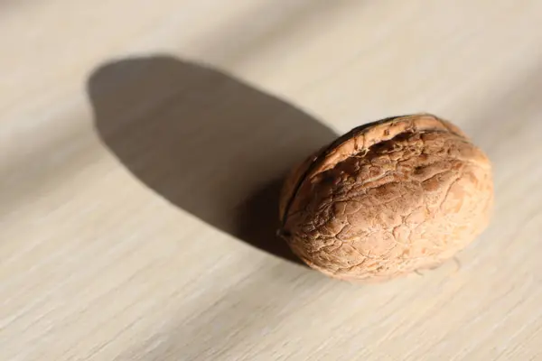 A walnut, a staple food ingredient in many cuisines, is placed on a wooden table, ready to be used in dishes, baked goods, and as a nutritious snack