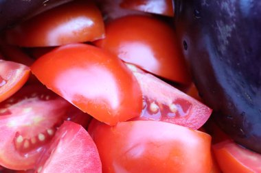 Yüksek çözünürlüklü, yakın plan bir görüntü dilimlenmiş domatesleri ve patlıcanları canlı, renkli bir ekranda gösteriyor..