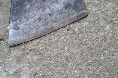 Beton bir yüzeyde yıpranmış bir bıçak, bir fotoğrafta kırsal ve yaşlanmış bir görünüm sergiliyor.