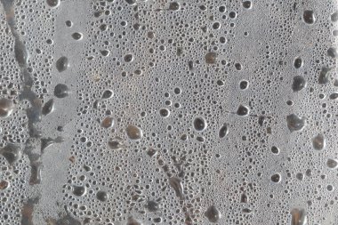 Hava kabarcıklarının ve küçük kusurların eşsiz bir kalıbını içeren gri beton yüzeyin detaylı görüntüsü