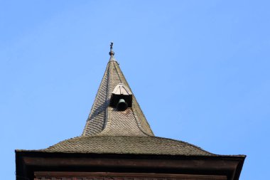 Bu resim, açık mavi gökyüzüne karşı, mimari detaylarını vurgulayan eski bir tarihi kilise kulesini gösteriyor.