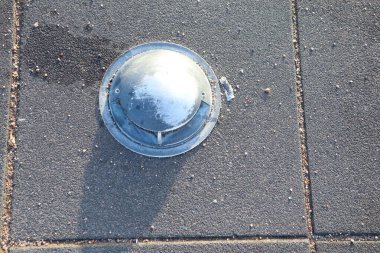 Açık havada fayanslarla döşenmiş metal bir nesne bir gölge yaratarak terk edilme ve gizem yaratıyor.