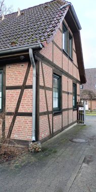 Ahşap bir çerçeveye sahip sağlam tuğla bir ev ve çekici bir çatı ile kaplanmış, büyüleyici bir görünüm yaratıyor