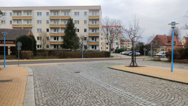 Resimli bir kaldırım taşı caddesi, ayak altında büyüleyici taşlar, arka planda belirgin duran sevimli bir bina ile birlikte.