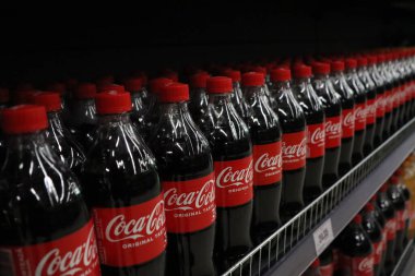 Bir süpermarket koridorunda düzgünce düzenlenmiş ve göz alıcı bir CocaCola şişesi sergisi bulunabilir