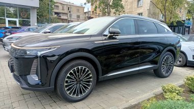 Canlı bir şehir sahnesinde sergilenen parlak siyah bir SUV modern otomotiv tasarımının özünü yakalıyor.