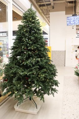 Güzel dekore edilmiş bir yapay Noel ağacı tatil döneminde modern bir perakende satış ortamında sergilenir.