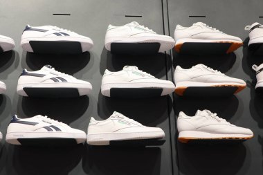 Modern ayakkabı trendlerinin sergilendiği çeşitli beyaz spor ayakkabıların modaya uygun ve şık bir düzenlemesi.