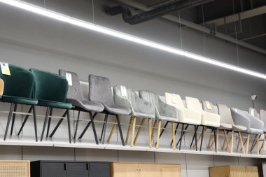 Çok çeşitli şık sandalyeler raflarda güzel bir şekilde dizilmiş, çağdaş tasarım seçenekleri sunuluyor.