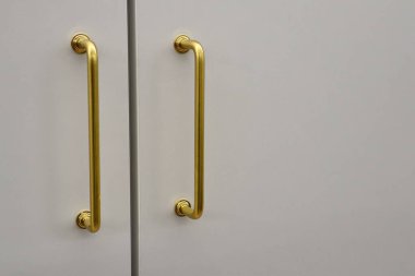 Zarif altın kulpları parlak beyaz bir dolabı tamamlıyor ve modern iç mekanlar için mükemmel hale getiriyor.