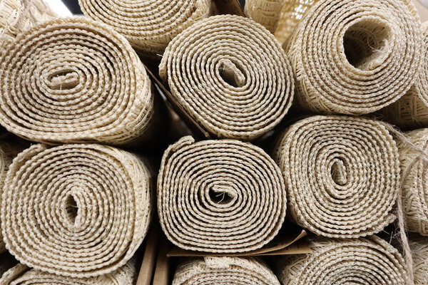 Stacked rolls of natural fiber mats highlight various sustainable flooring material options available
