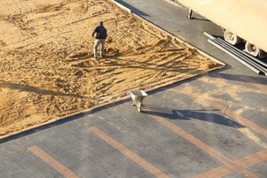 Çalışkan bir işçi aktif bir inşaat sahasındaki kritik zemin hazırlama sürecini dikkatle denetliyor.