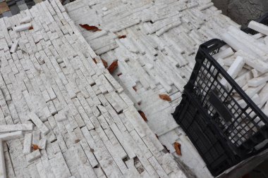 Dağınık, kaotik bir beyaz taş yığını. Düşen yapraklar arasında dikkatsizce dağılmış. Yanında da siyah bir sepet.