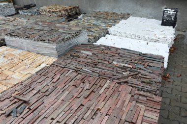 İnşaat amaçları ve kullanımı için yığınlar halinde düzenlenmiş çeşitli ve çeşitli kiremitler ve tuğlalar.