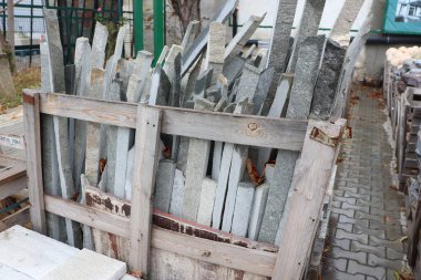 Kırsal ahşap bir sandık, ağzına kadar çeşitli taş levhalarla dolu, açık hava depolama alanını genişletiyor.