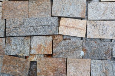 Görsel olarak çarpıcı olan eşsiz tahta dizaynlar içeren desenli taş bir duvara yakın plan.