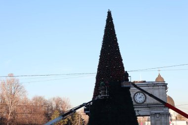 Güzel süslenmiş bir Noel ağacı bu sevinçli günde şaşırtıcı derecede açık mavi bir gökyüzüne karşı şekil alıyor.
