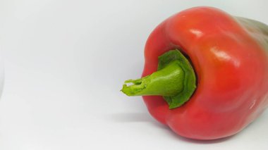 Taze, canlı kırmızı bir dolma biber parlak yeşil sapıyla birlikte parlak yüzeyini sergiliyor.