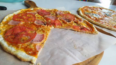 Taze domatesli, erimiş peynirli ve ahşap bir tahtada lezzetli bir pizzanın tadını çıkar.