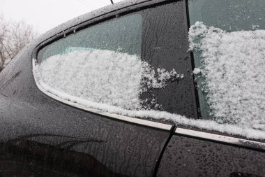 Kış mevsiminde tamamen buzla kaplı ve parlayan yağmur damlalarıyla kaplı bir arabanın yakın çekim görüntüsü