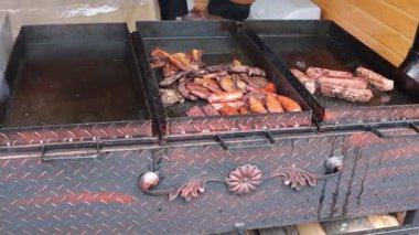 Canlı bir barbekü ızgarası. Açık hava şenliklerinde ızgara yapmaya hazır lezzetli et çeşitleri sergiliyor.