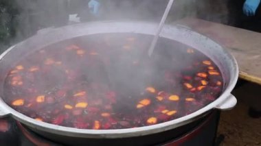 Kaynayan, kokulu meyve güveciyle dolu büyük, davetkar bir tencere, canlı bir açık hava ortamında buhar salıyor.