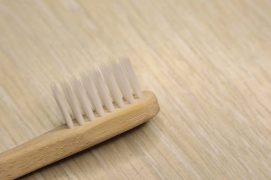 Bu resim bambu bir diş fırçasının ahşap bir yüzeyde güzelce dinlenirken yakın çekimini yakalar.