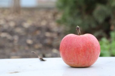 Canlı ve taze kırmızı bir elma ahşap bir masanın üzerine güzel bir şekilde yerleştirilmiş, büyüleyici doğal güzelliğini sergiliyor.