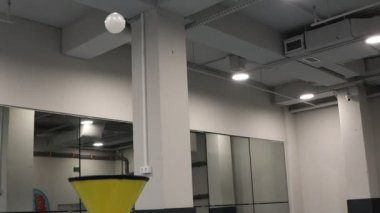 Dinamik bir atış, geniş bir spor salonunda yansıtıcı yüzeylerle zarafetle süzülen bir topu yakalar.