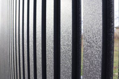 A closeup shot of a frosted glass piece with a black metal fence, creating a captivating abstract pattern clipart