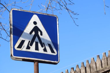 Açık ve görünür bir yaya geçidi işareti parlak bir mavi gökyüzü arka planına karşı göze çarpıyor.