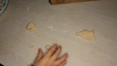 Küçük bir çocuk küçük elleri, ahşap bir yüzeyde yumuşak hamuru çeşitli eğlenceli ve heyecan verici şekillerde şekillendiriyor.