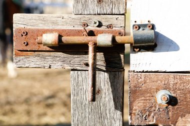 Eskimiş ve yıpranmış bir kilit kırsal ahşap bir kapıda, güzel bir şekilde eski malzemelerinin cazibesini sergiliyor.