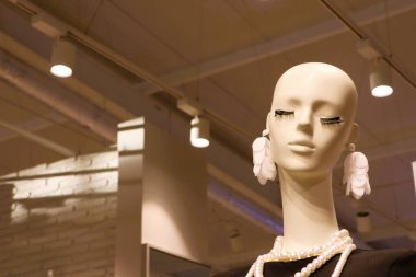 Zarif inciler ve çarpıcı küpelerle süslenmiş şık bir manken, modern perakende moda trendleri sergiliyor.