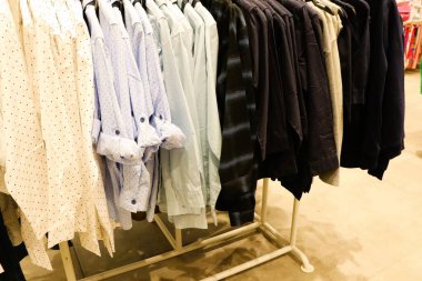 En son moda eğilimlerini sergileyen, bir askıda sergilenen şık bir gömlek koleksiyonu.