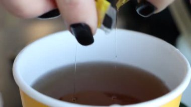 Bir el ustalıkla olgun bir limonu fincana sıkıştırıyor, çayın ve sıcak suyun tadını ve kokusunu arttırıyor.