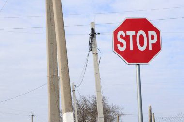 Bir dur işaretinin iyi tanımlanmış ve net bir görüntüsü, kırsal bir ortamda elektrik direğinin yanına yerleştirilmiş.