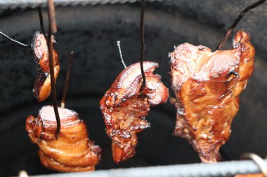 Tütsülenmiş et yavaşça fırında asılı duruyor, BBQ mükemmelliğinin ve lezzetinin gerçek özünü gözler önüne seriyor.