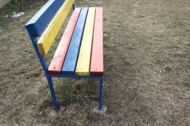 Canlı ve davetkar bir bank. Çimenli arka planda çok çeşitli renkli levhalar var.