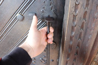 Bir el, yapısında karmaşık tasarımlar ve dokular olan güzel bir kapı kolunu tutar.