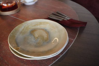 Güzel tasarlanmış bir tabak ve zarif gümüş takımlar kırsal ahşap bir masa üzerinde zarif bir şekilde düzenlenmiştir.